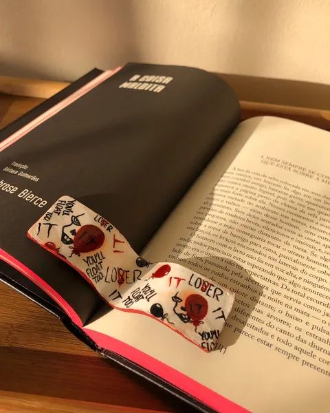 Hand-painted white bookmark with red balloons and the words "You'll float too" and "LOSER" lying across the pages of an open book.