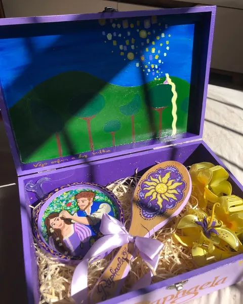 Open purple wooden keepsake box painted with the Tangled lantern scene inside the lid, holding a painted hairbrush, a hand mirror with Rapunzel and Flynn, and yellow hair clips.
